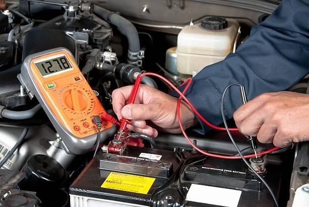 Person testing a car battery with a multimeter, showing 12.78 volts.