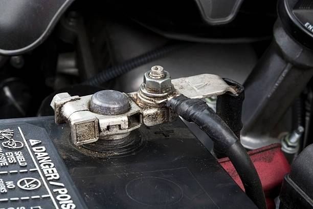 Car battery terminal with corroded clamp and black cable.