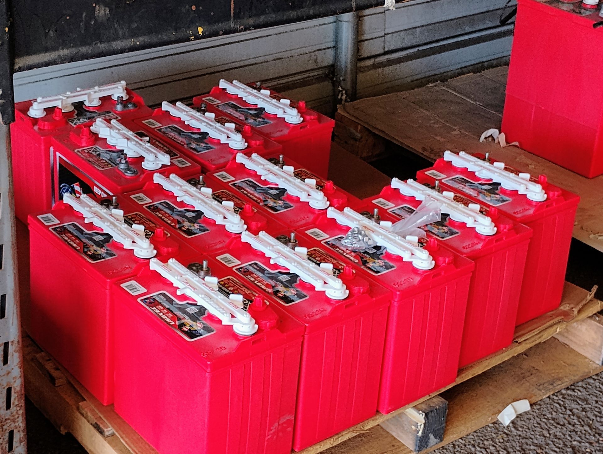 Red batteries stacked on a pallet, possibly for transport or storage.
