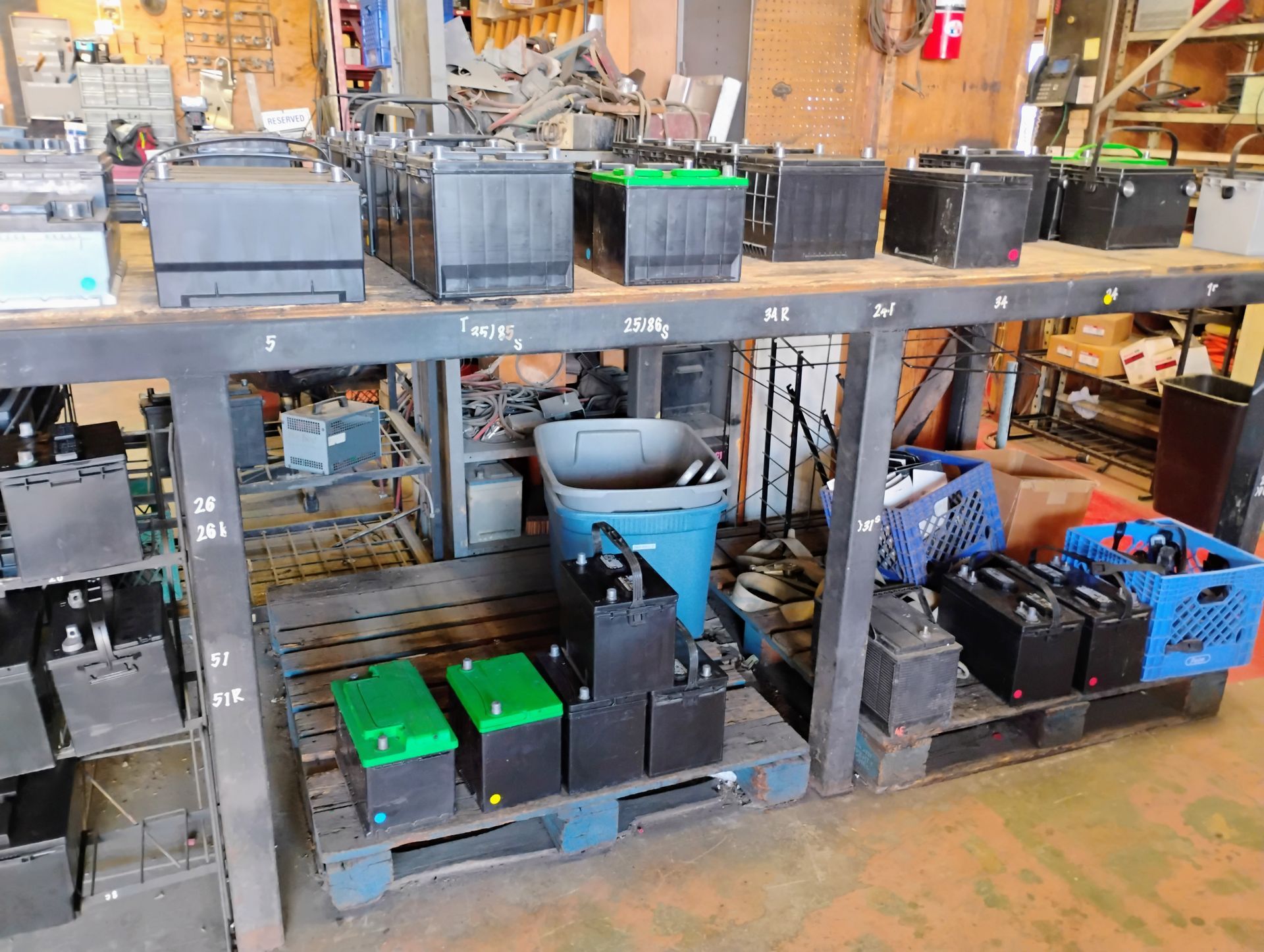 Batteries on metal shelves, various sizes and colors, in a workshop setting.