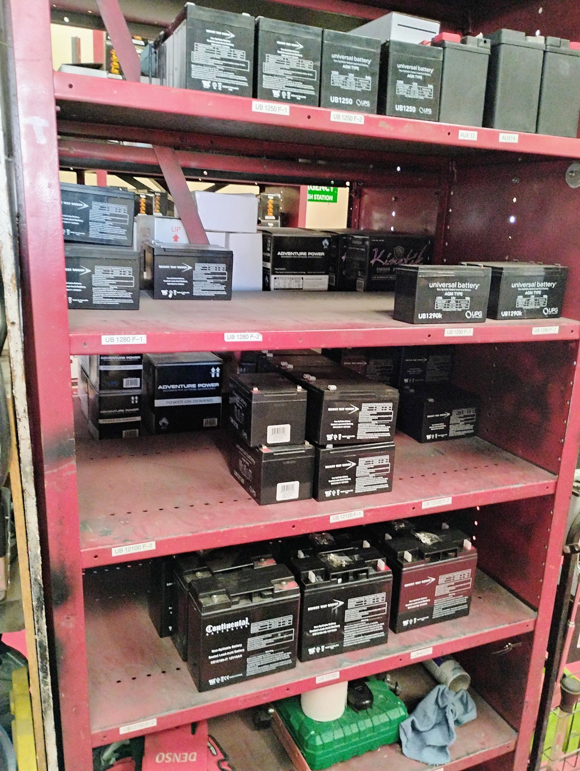 Red shelving unit filled with various black batteries.