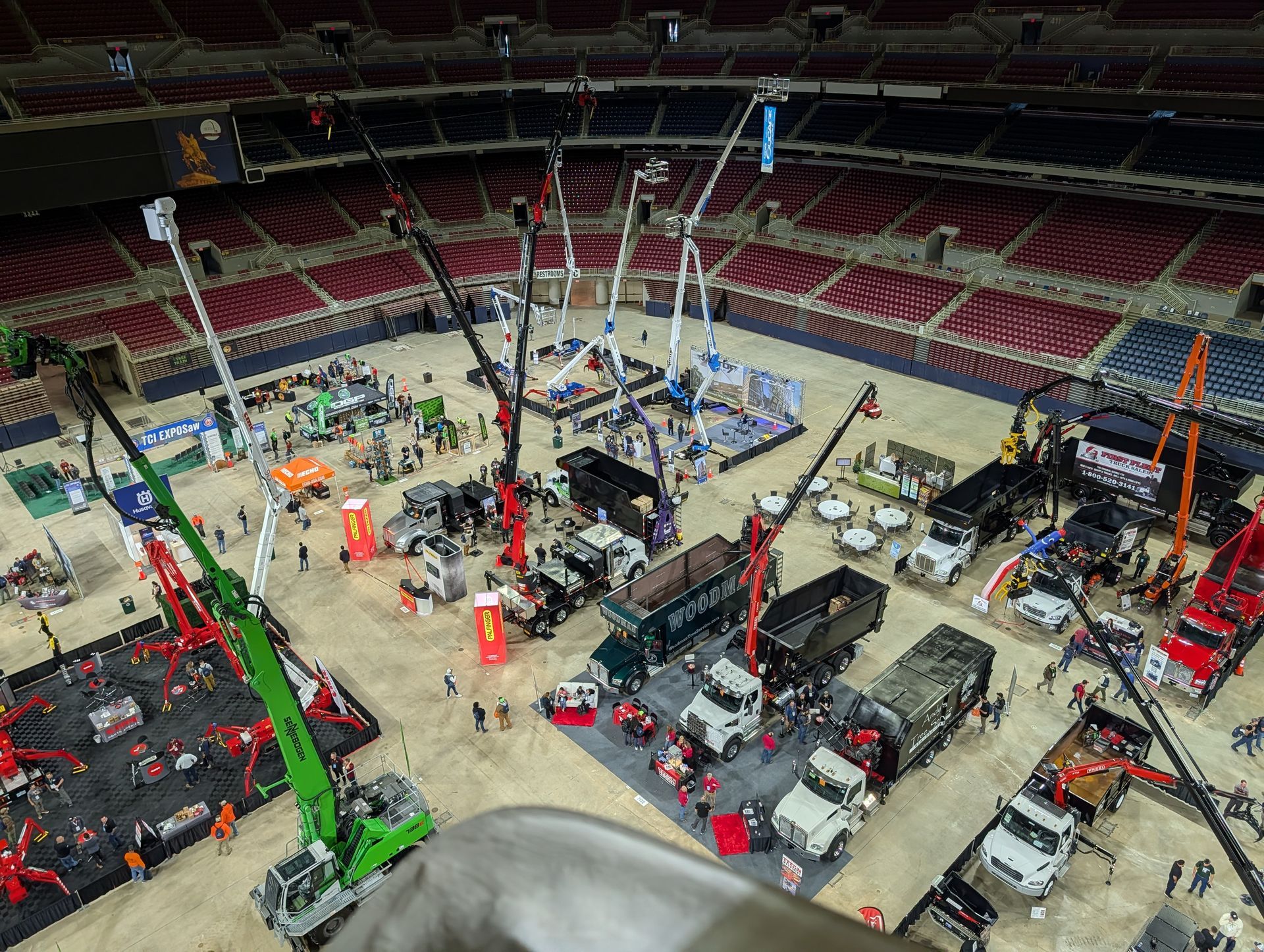 Indoor stadium floor packed with equipment, cranes, and workers setting up an event.