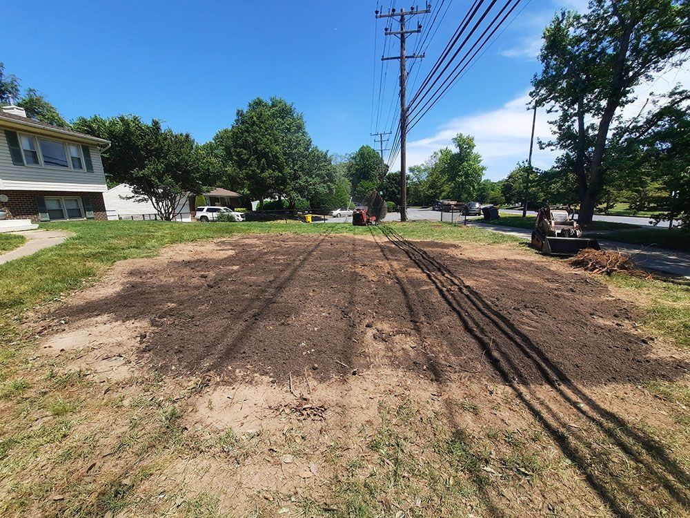 Roadwork in a residential street with dirt, utility poles, and a house on the left.