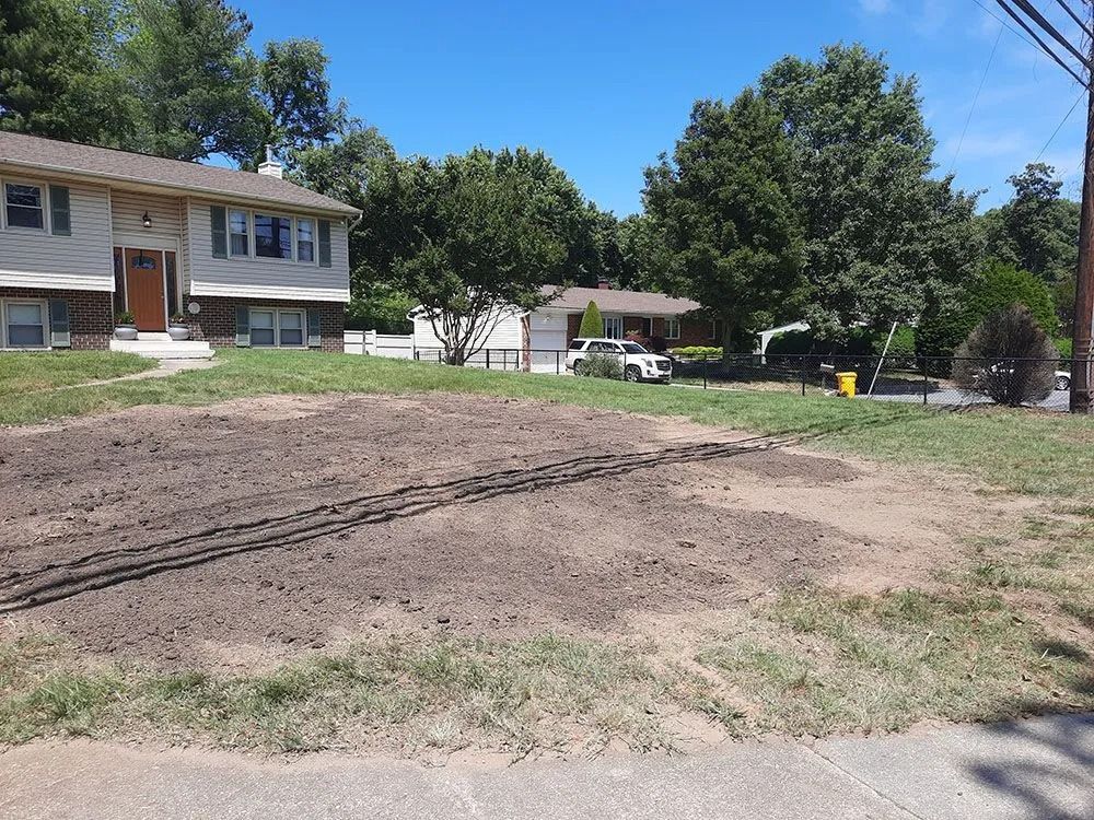 Freshly graded dirt lot beside apartment buildings under a clear blue sky