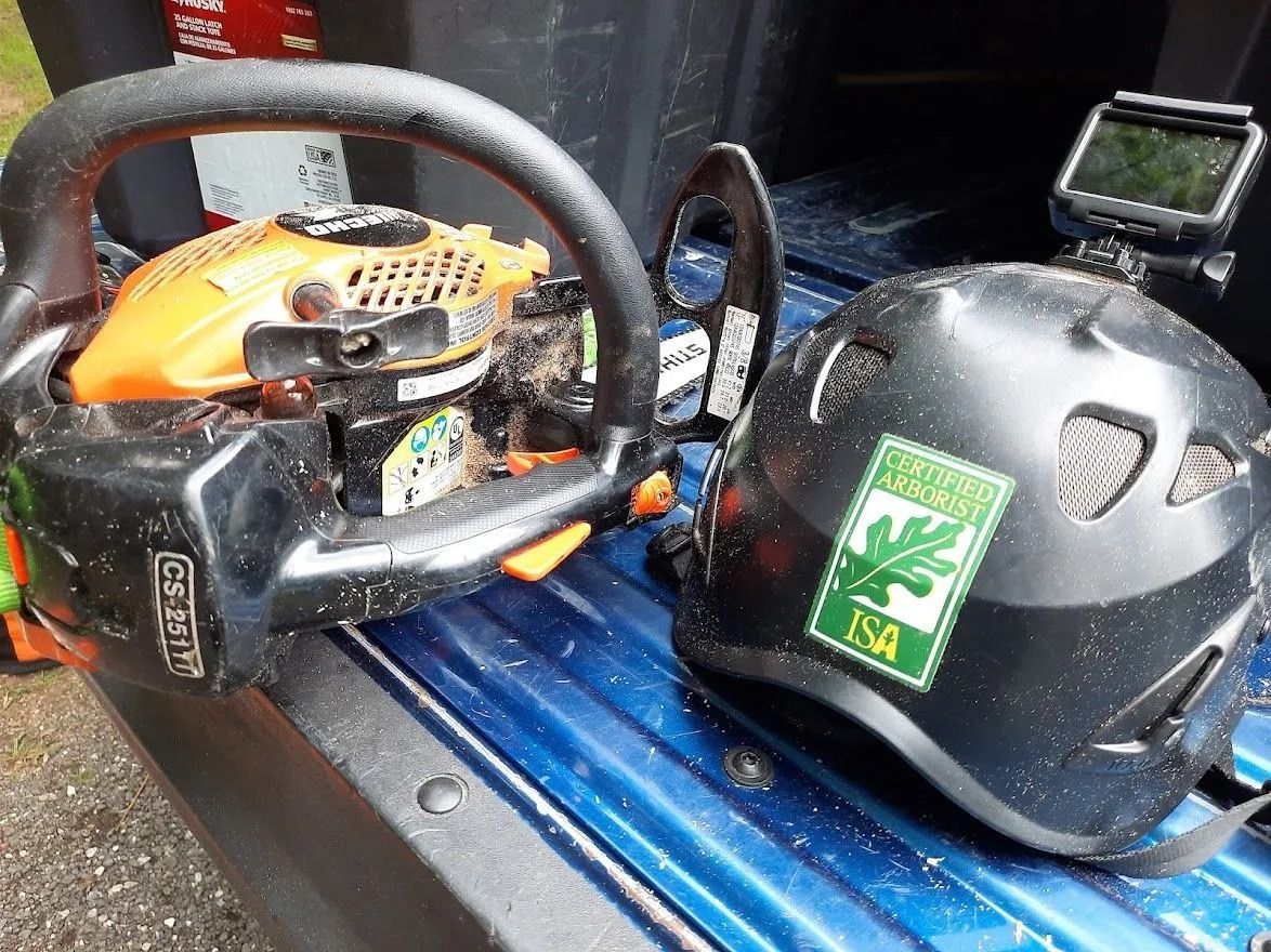 Orange chainsaw and black safety helmet on a vehicle floorboard.