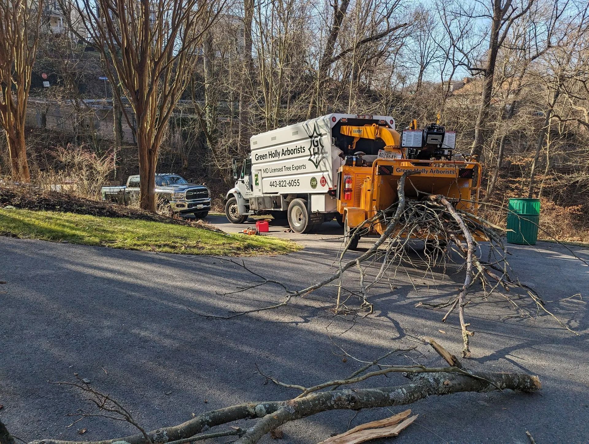 Road crew truck removing fallen tree branches from a roadside in a wooded area