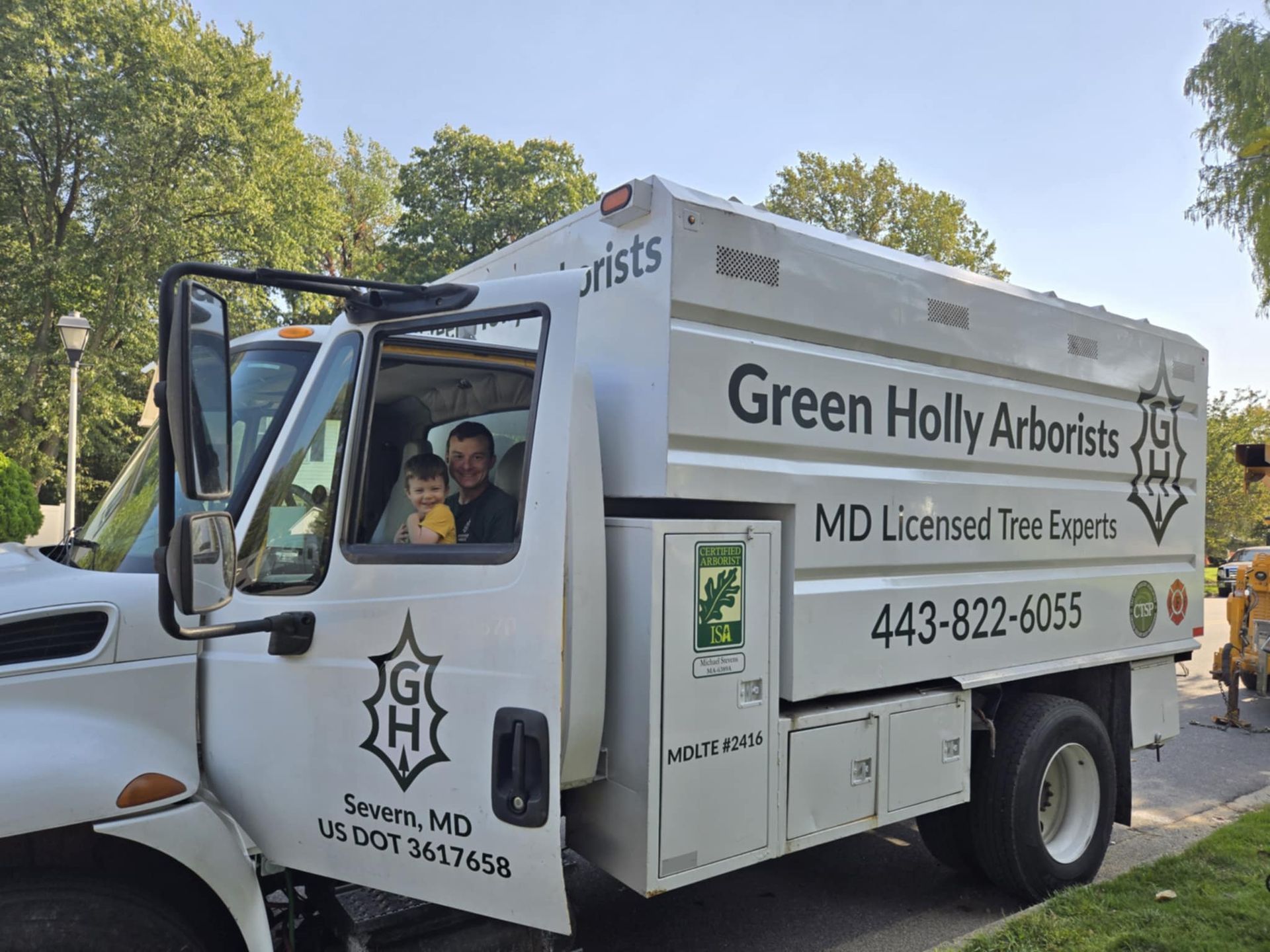 Green Holly Arborists truck parked outdoors with driver visible in the cab.