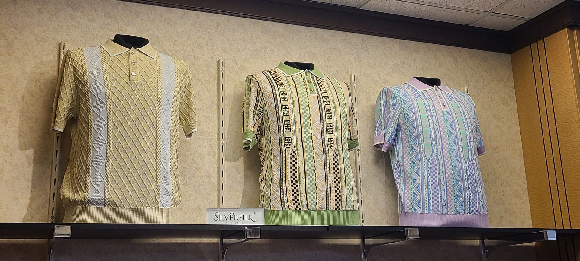 Three patterned blouses displayed on hangers in a store or showroom cabinet