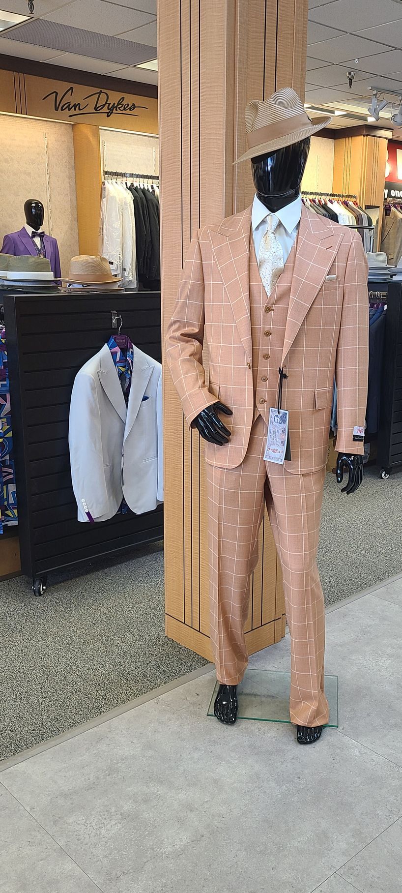 Mannequin wearing a peach plaid suit and hat in a clothing store display.