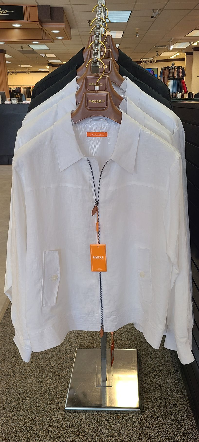 White long-sleeve button-up shirt on a clothing rack in a store, with an orange tag underneath