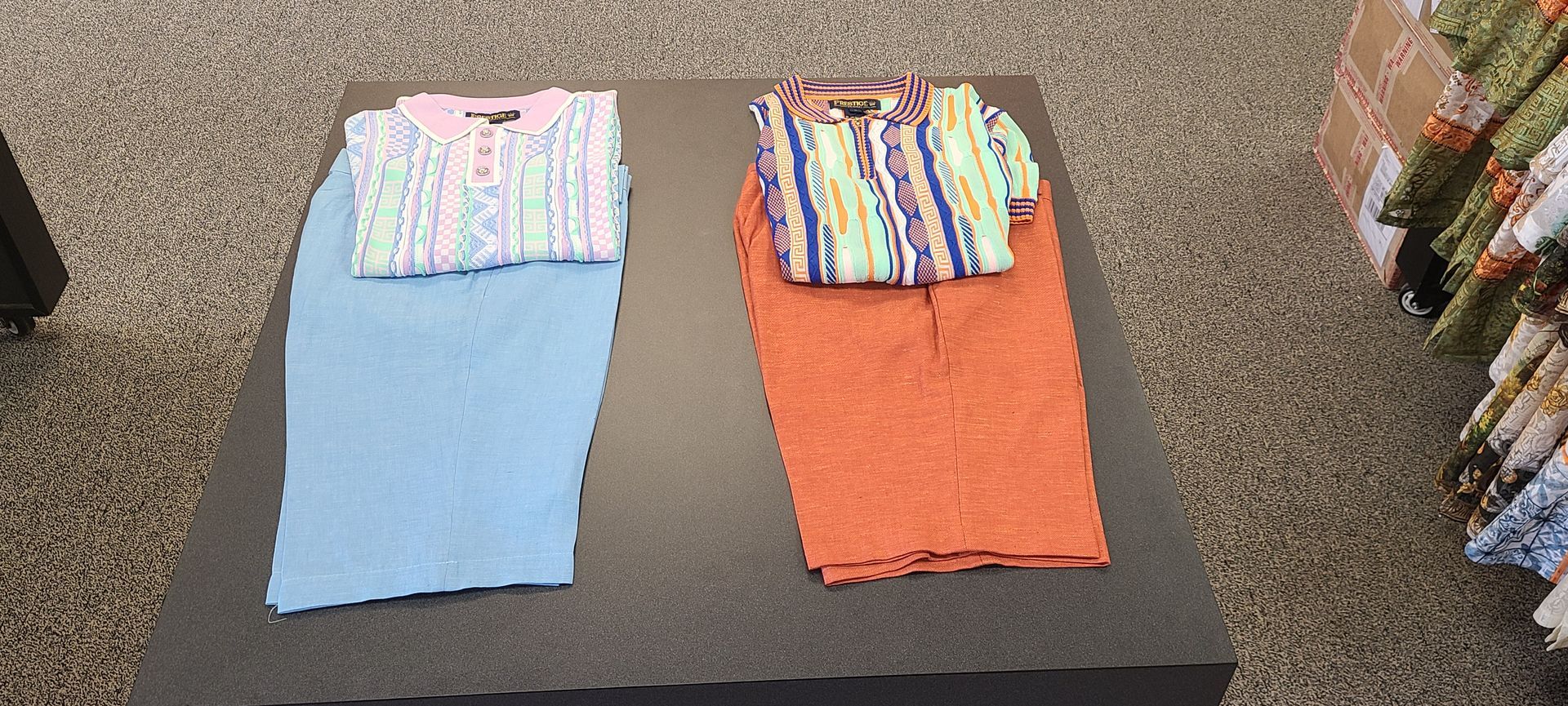 Two folded towels, light blue and orange, each topped with a striped cloth, on a dark table.