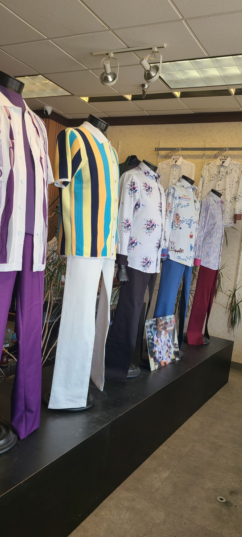 Clothing rack with colorful shirts, pants, and patterned garments displayed in a store.