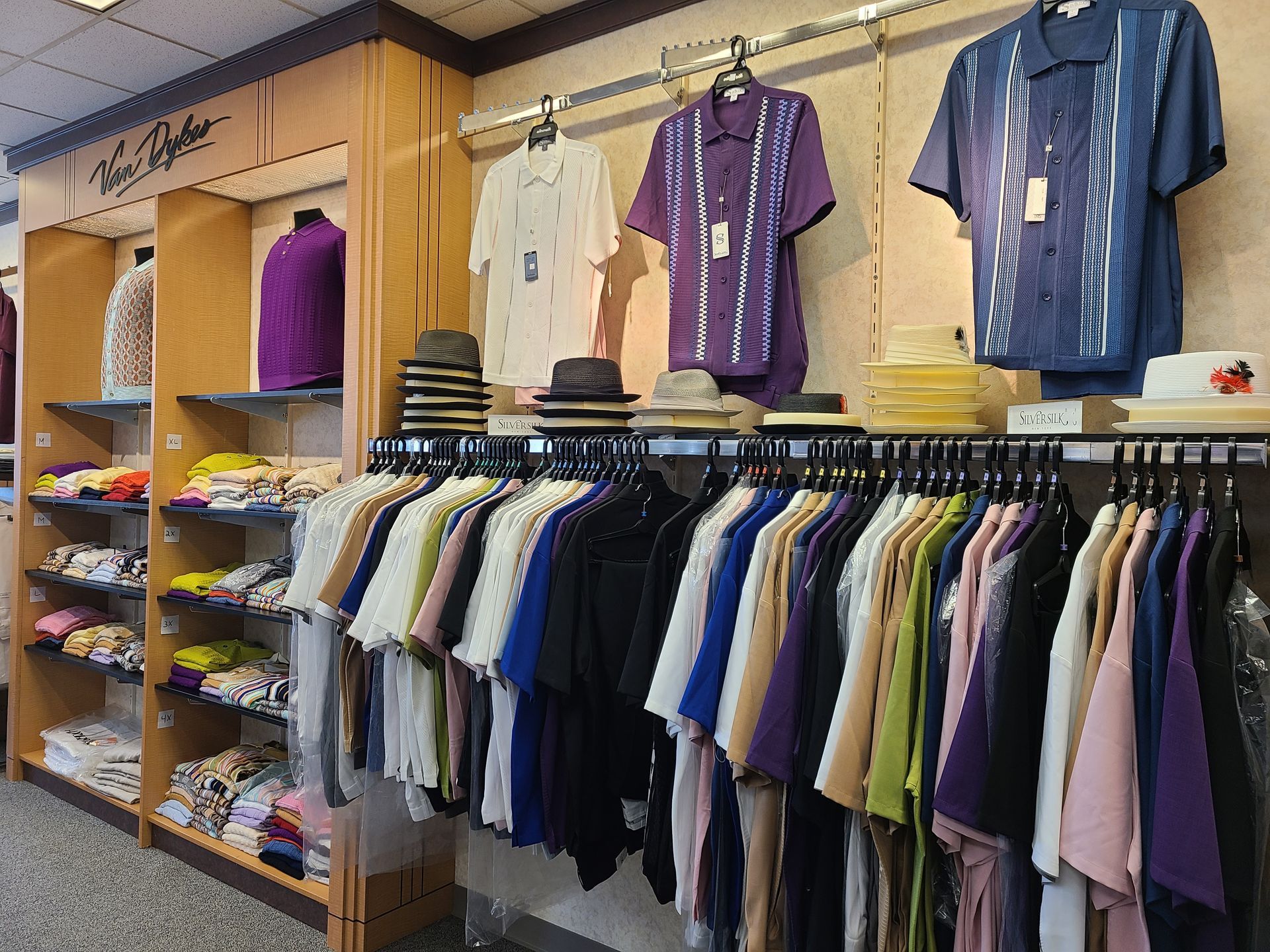 Clothing store display with folded shirts, hanging garments, and wall-mounted jerseys on wooden shelves