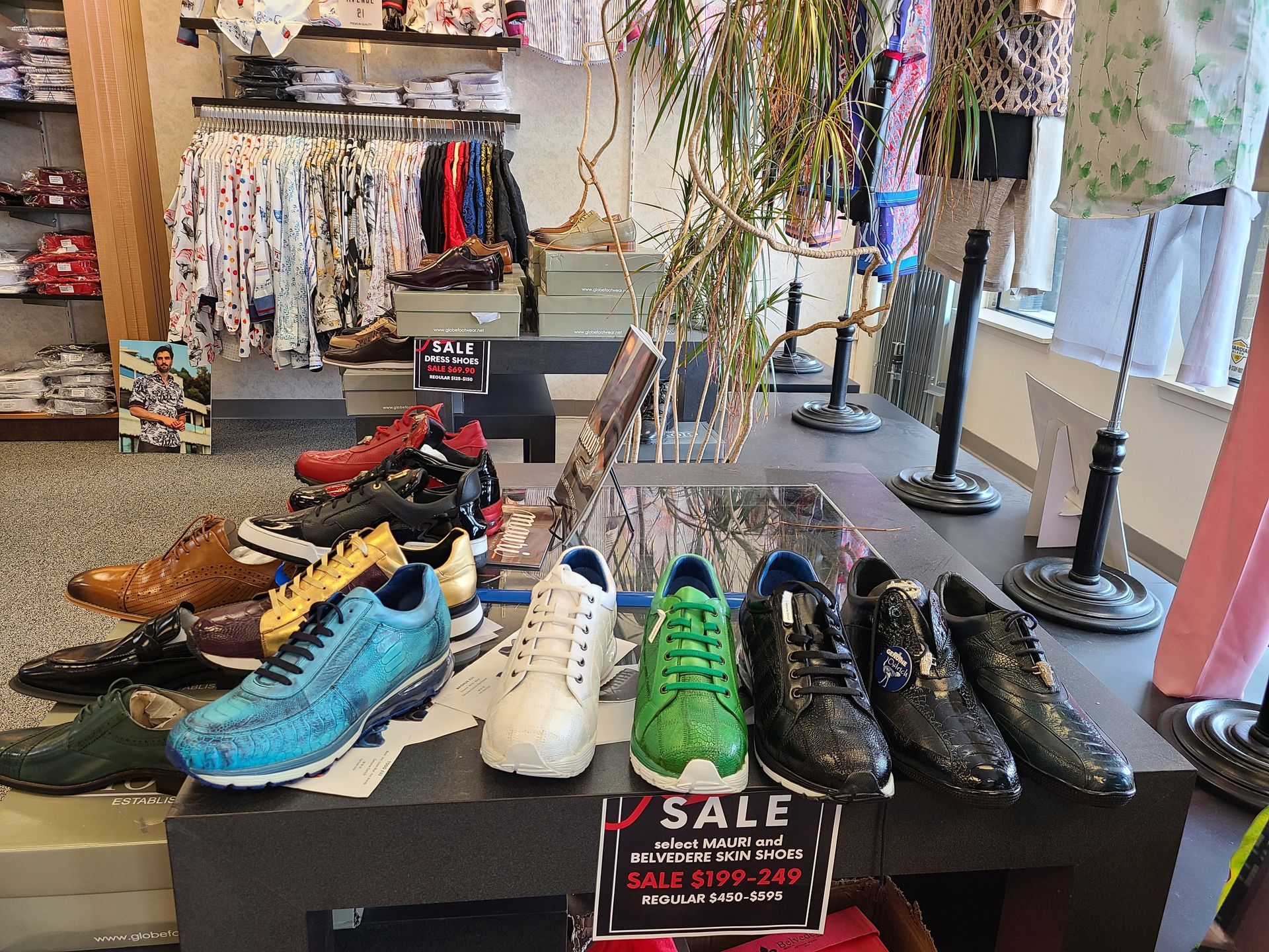 Sneakers displayed on a sale table in a clothing store, with colorful shoes and a rack of apparel behind.