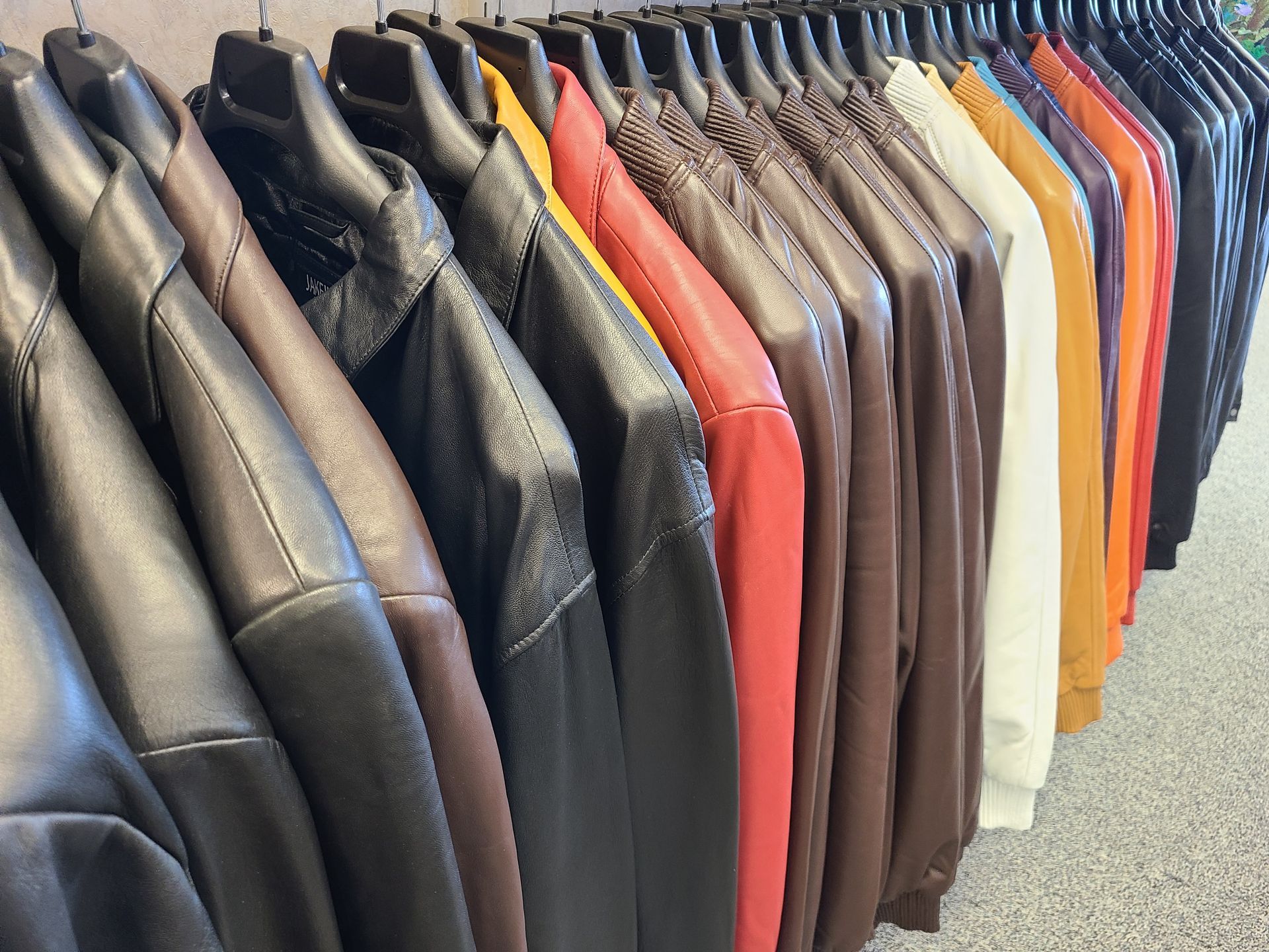 Row of colorful leather jackets hanging on a clothing rack indoors
