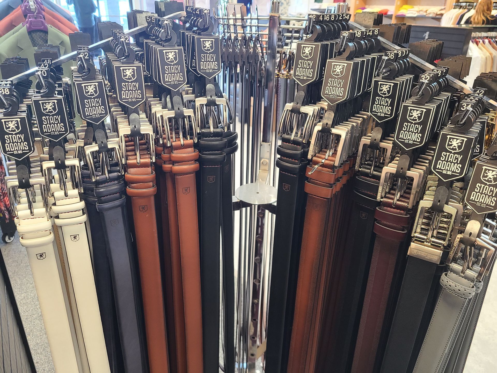 Assorted umbrellas with patterned handles and canopies are displayed tightly packed in a store rack
