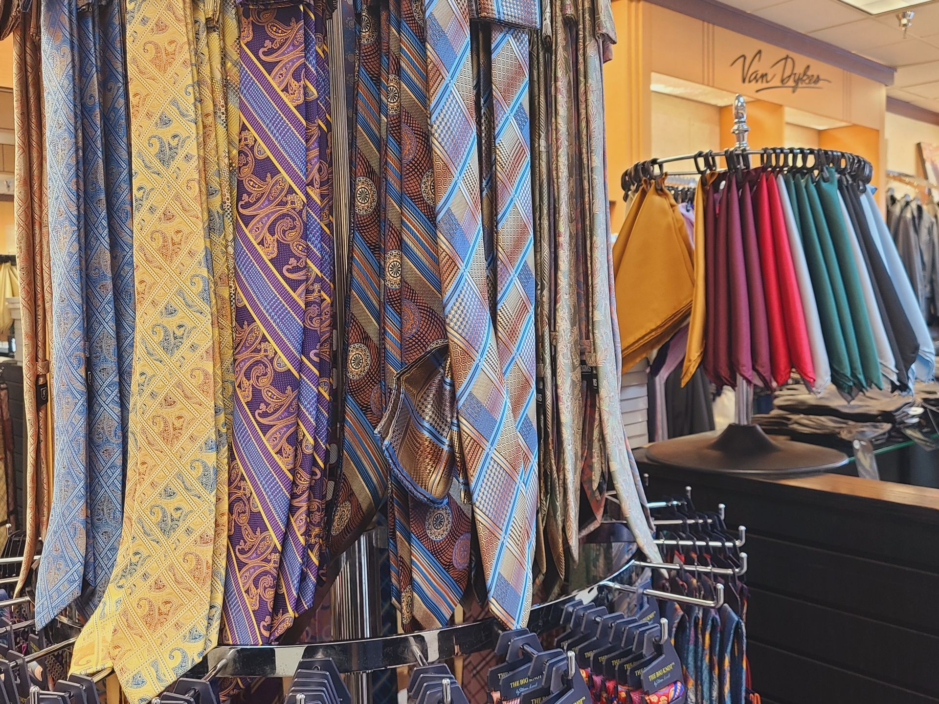 Colorful patterned scarves and clothing displayed on racks in a boutique shop