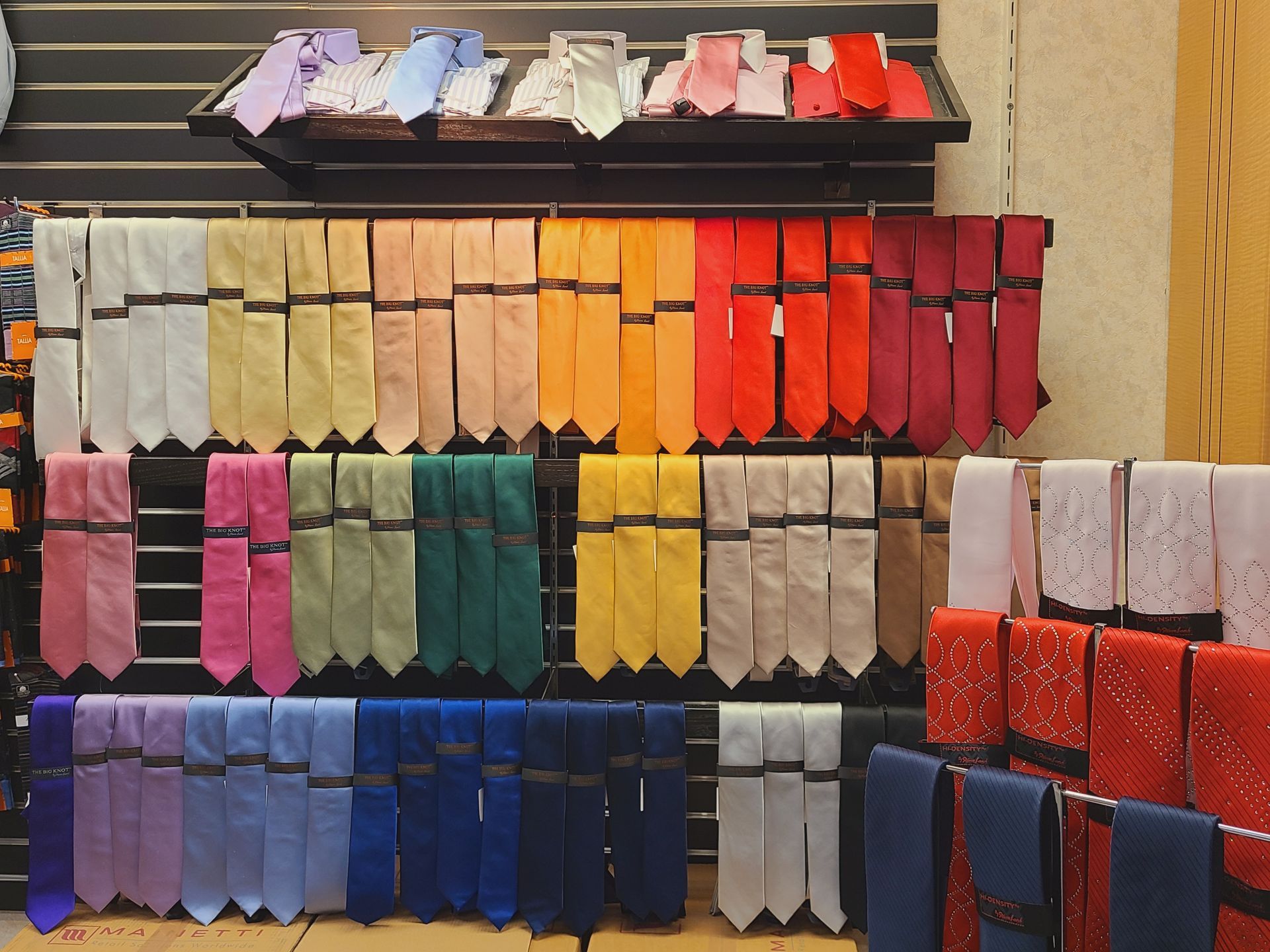Rows of colorful socks are displayed on store shelves, arranged by color gradients.