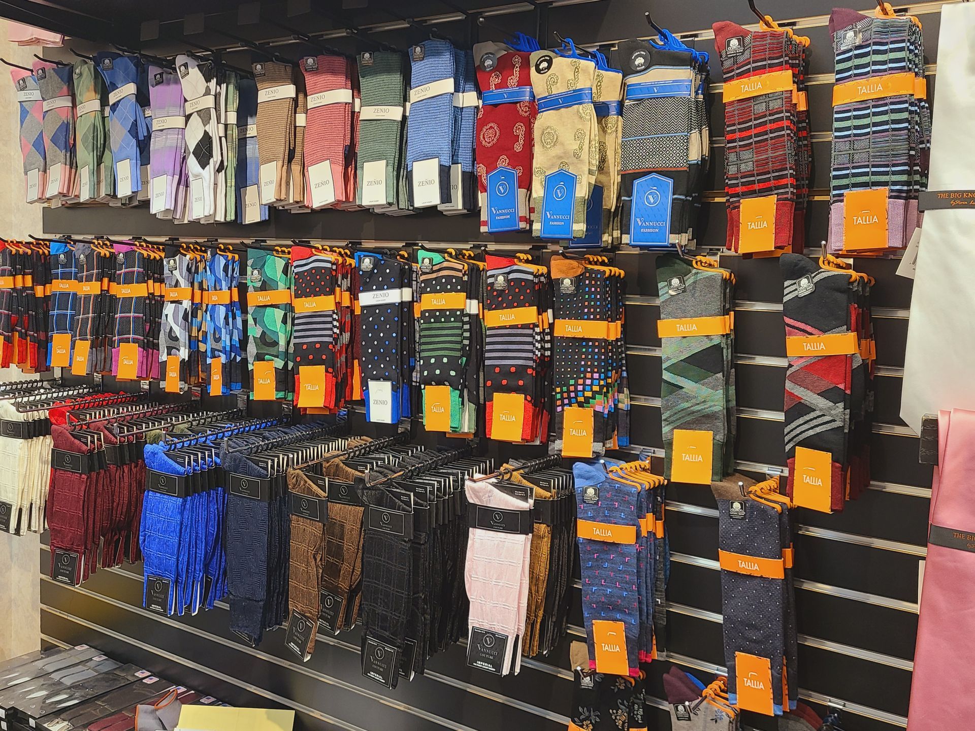 Sock display in a store aisle, with rows of colorful packaged and hanging socks on shelves.