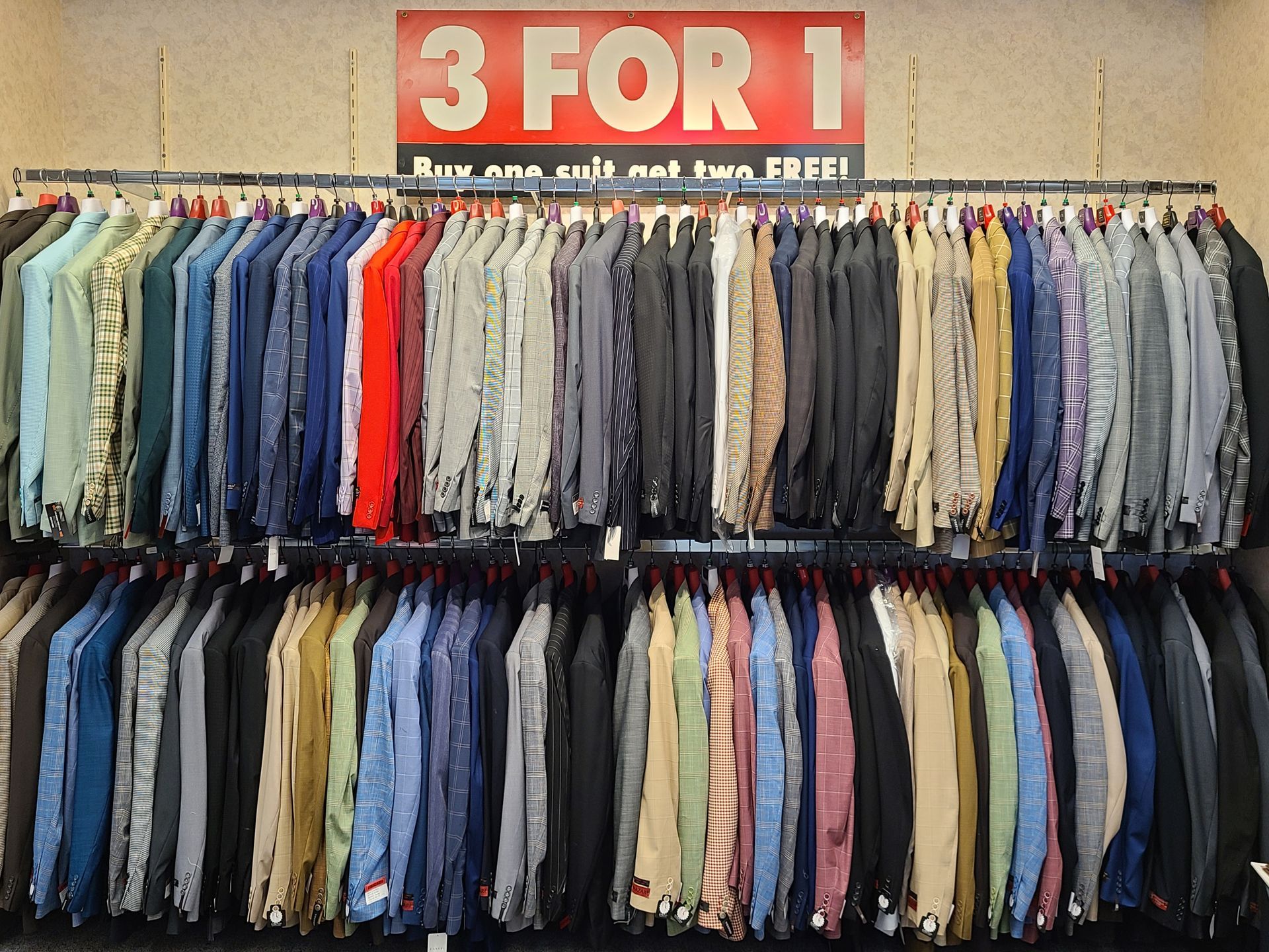 Clothing rack with assorted shirts and a red 3 FOR 1 sale sign above it