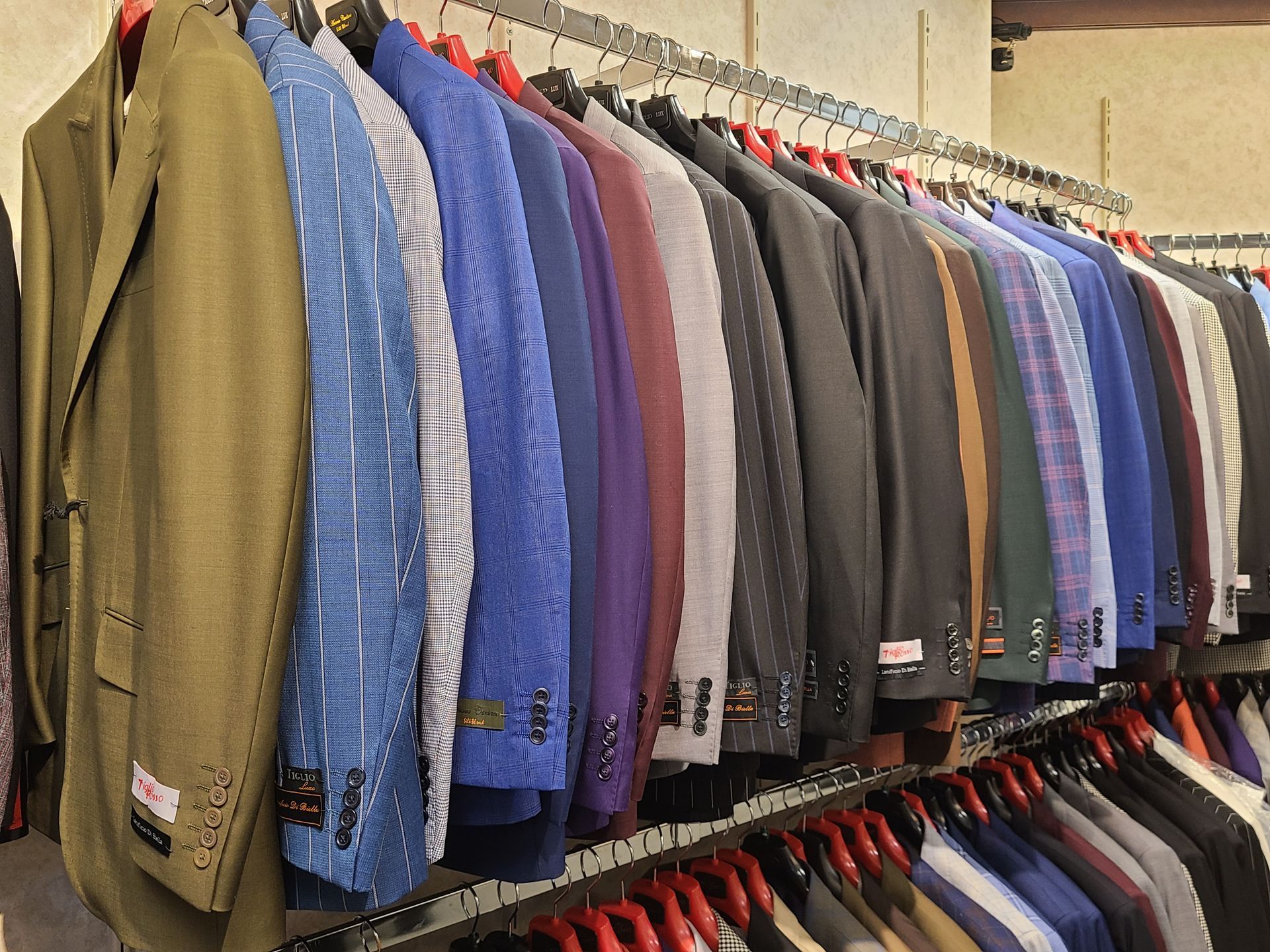 Row of colorful suits and jackets hanging neatly on clothing racks in a store
