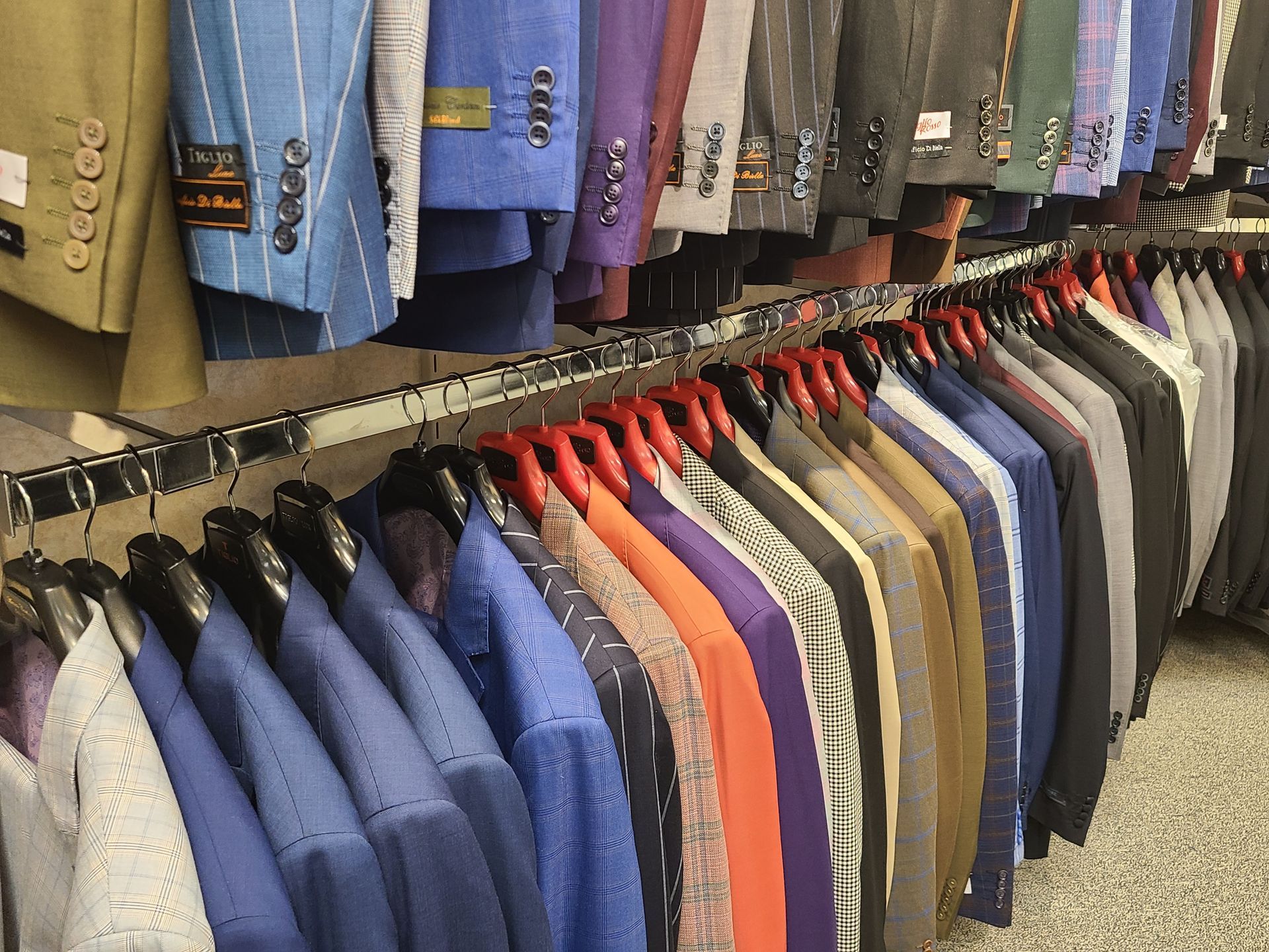 Colorful shirts and jackets hanging on racks in a clothing store.