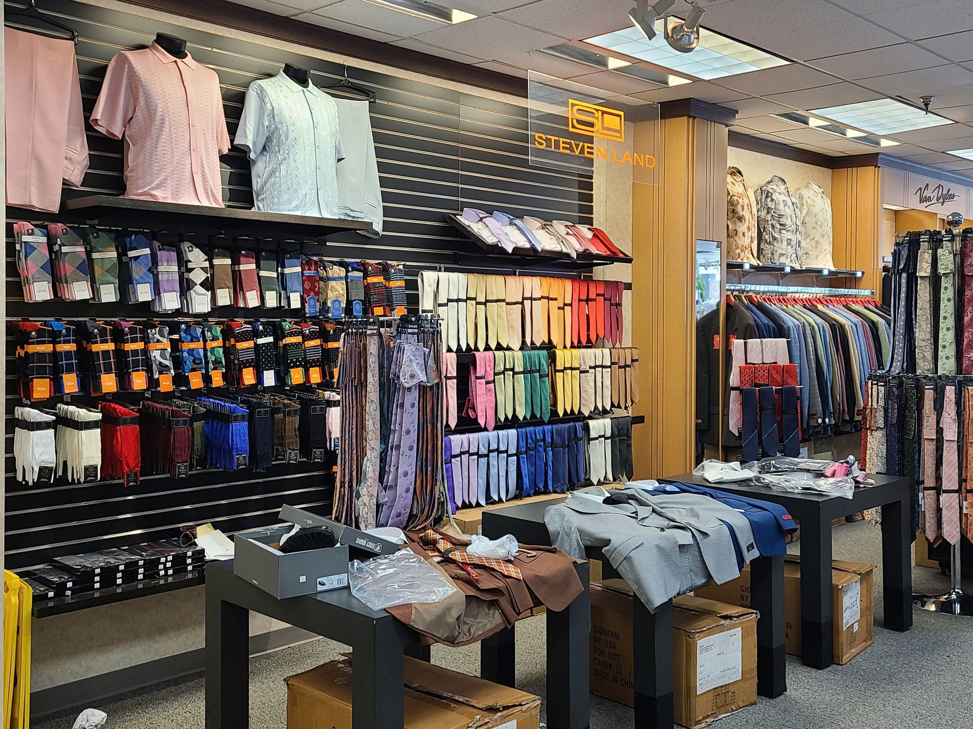 Clothing store display with folded shirts, socks, and jeans on shelves and tables.