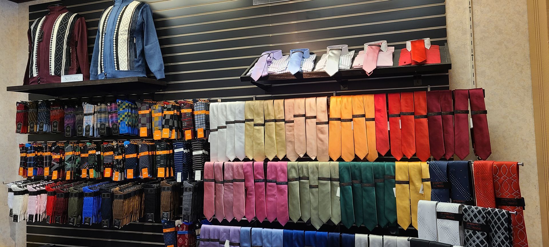 Display of colorful scarves and gloves arranged on store shelves and racks.