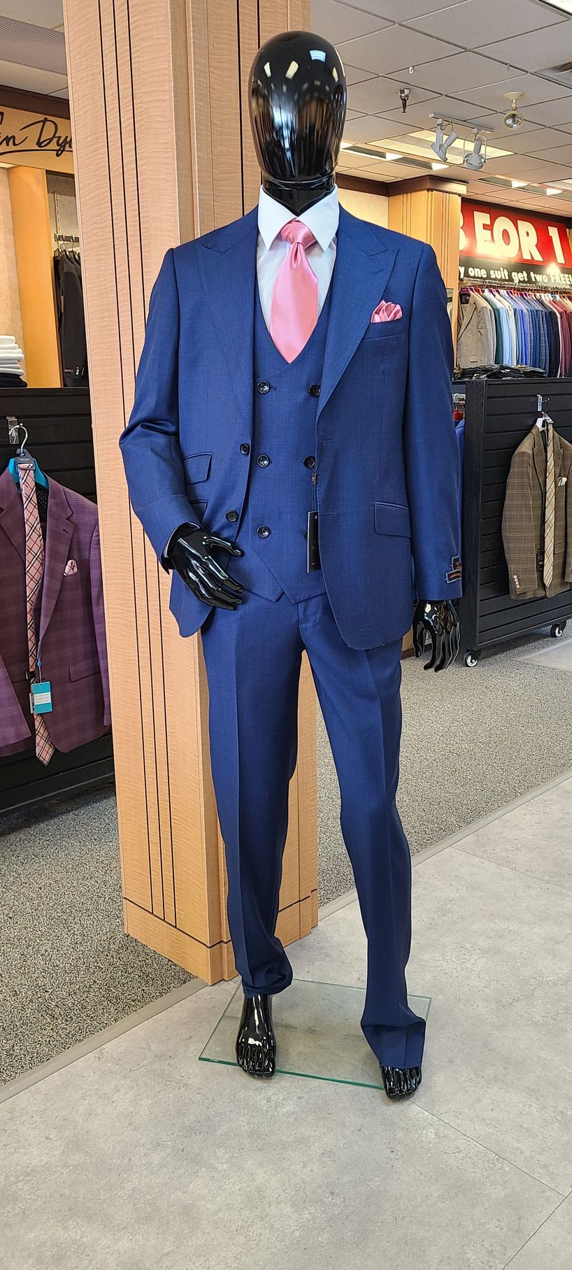Mannequin in a blue suit with pink tie standing in a clothing store display