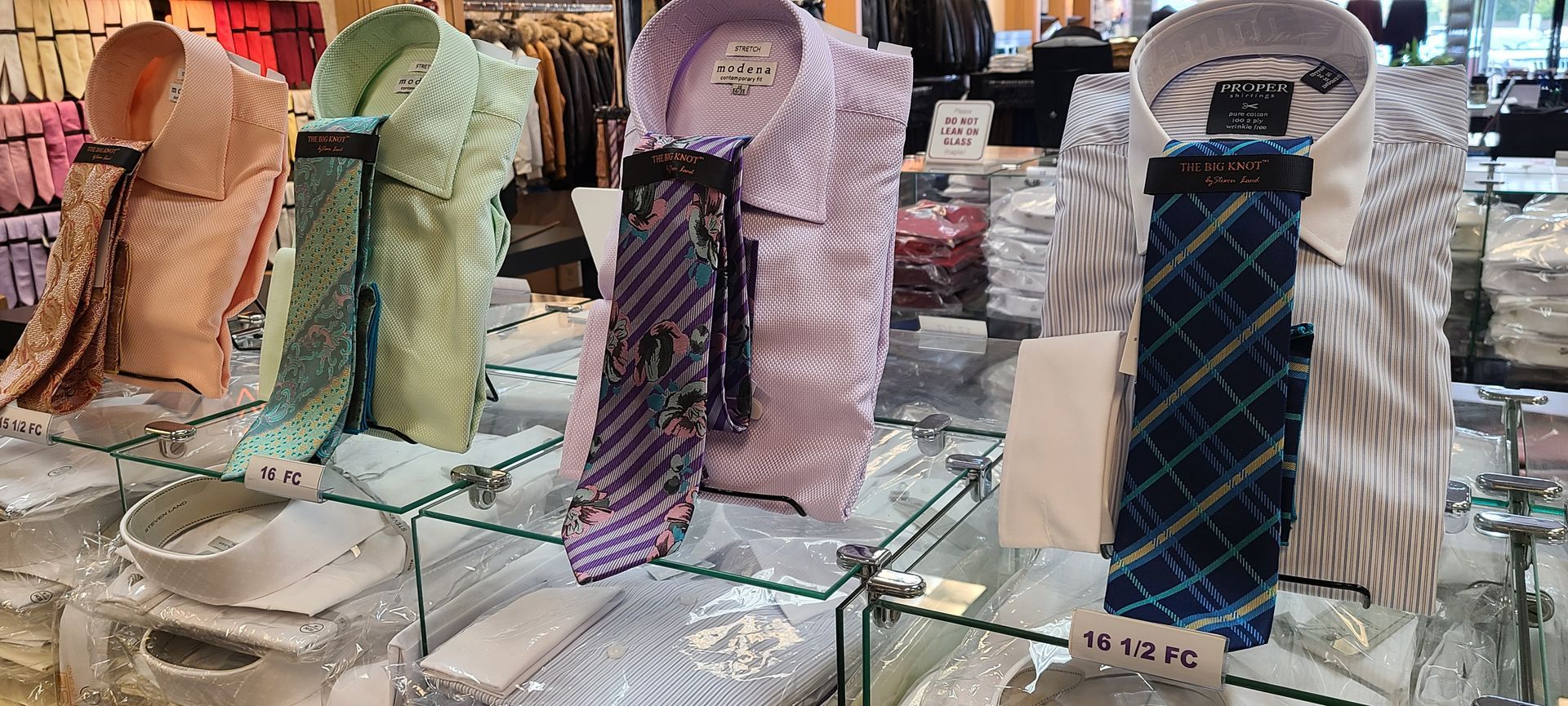 Four colorful patterned neckties displayed on stands at a market stall