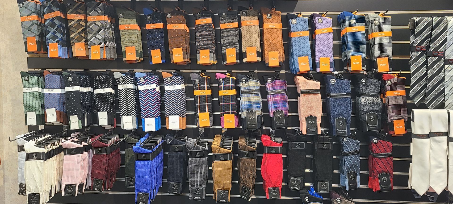Wall display of assorted socks and accessories in rows, with colorful packs and a striped section on the right.
