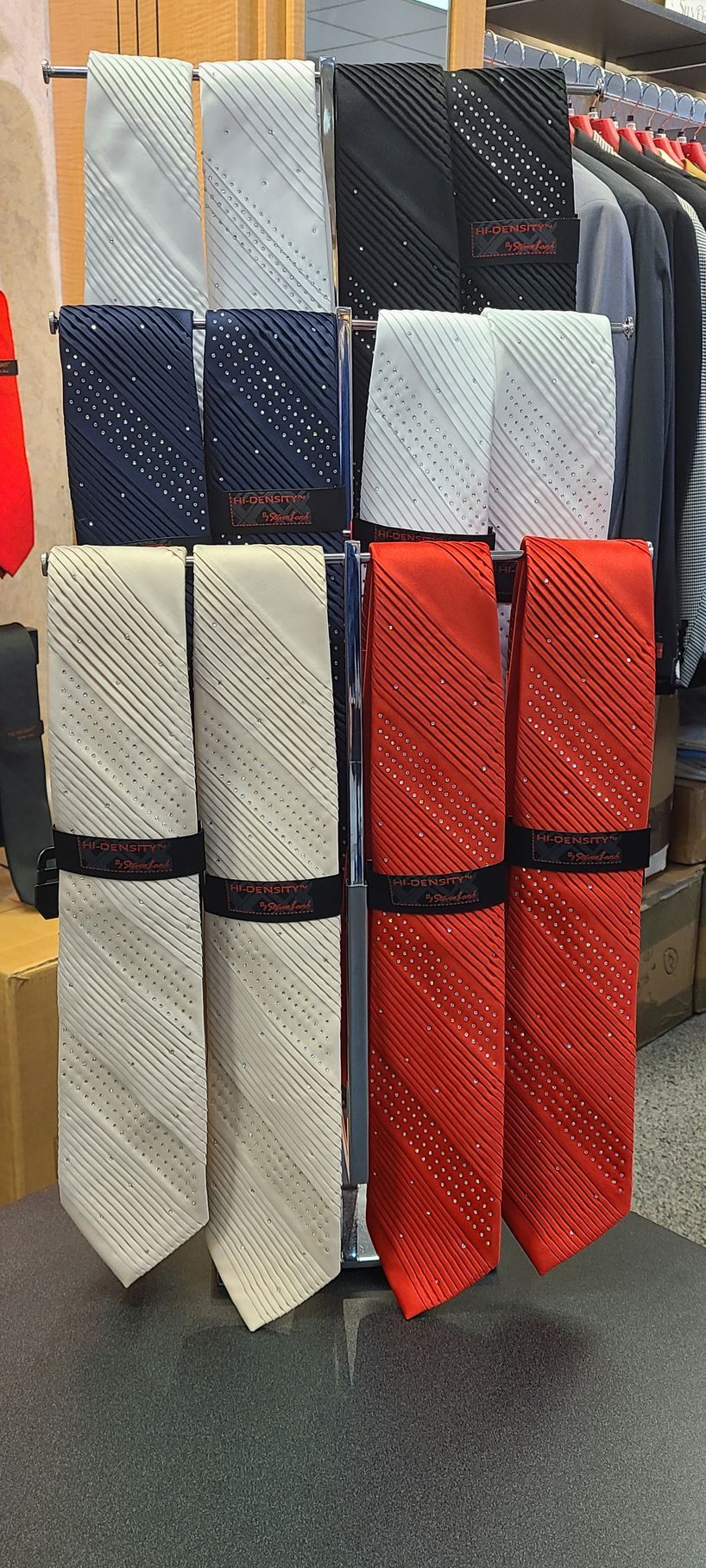 Neckties displayed on a store rack in white, blue, black, gray, and red patterns
