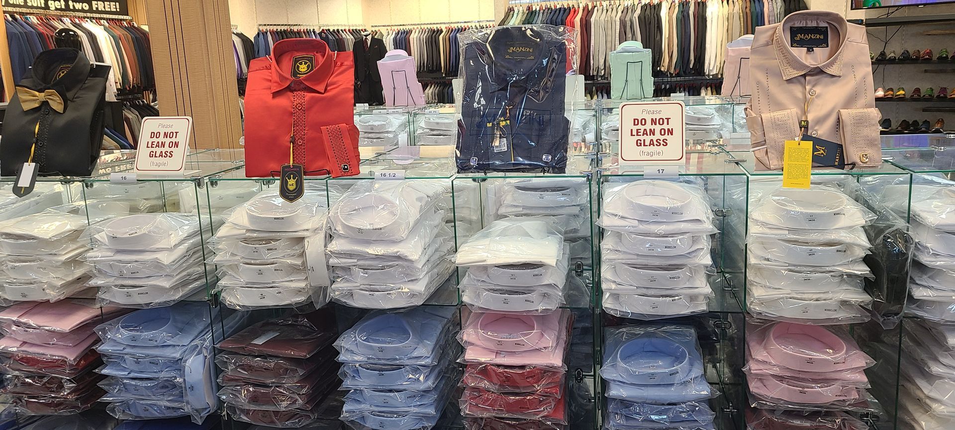 Clothing store display with stacks of folded shirts and hanging tops in assorted colors