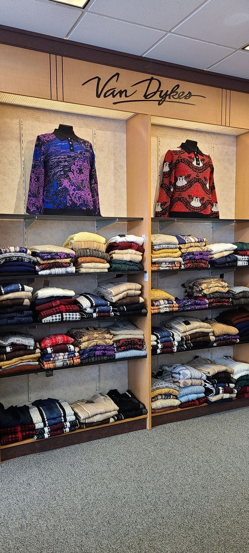 Clothing display wall with folded sweaters and two colorful jackets in a store