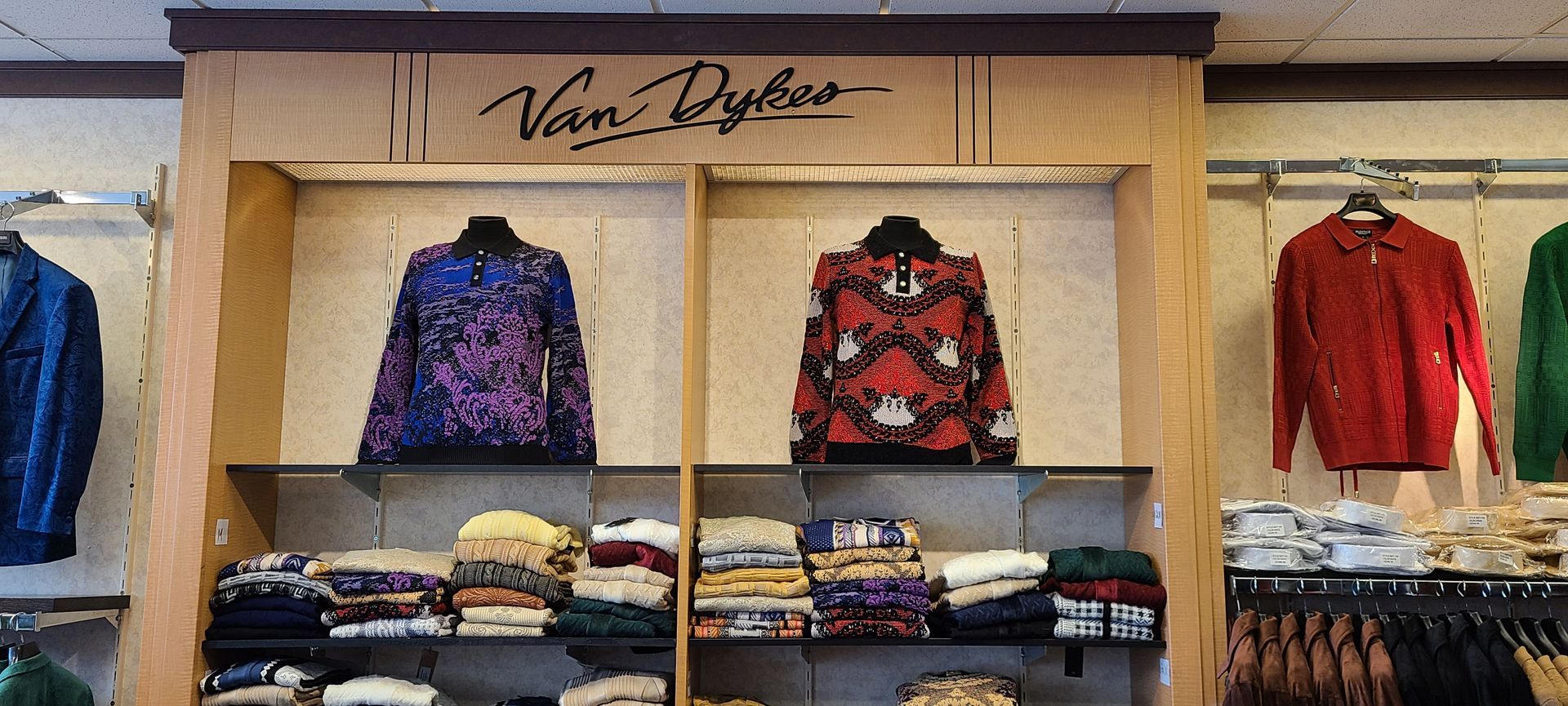 Clothing display with folded sweaters and colorful jackets on shelves in a store.