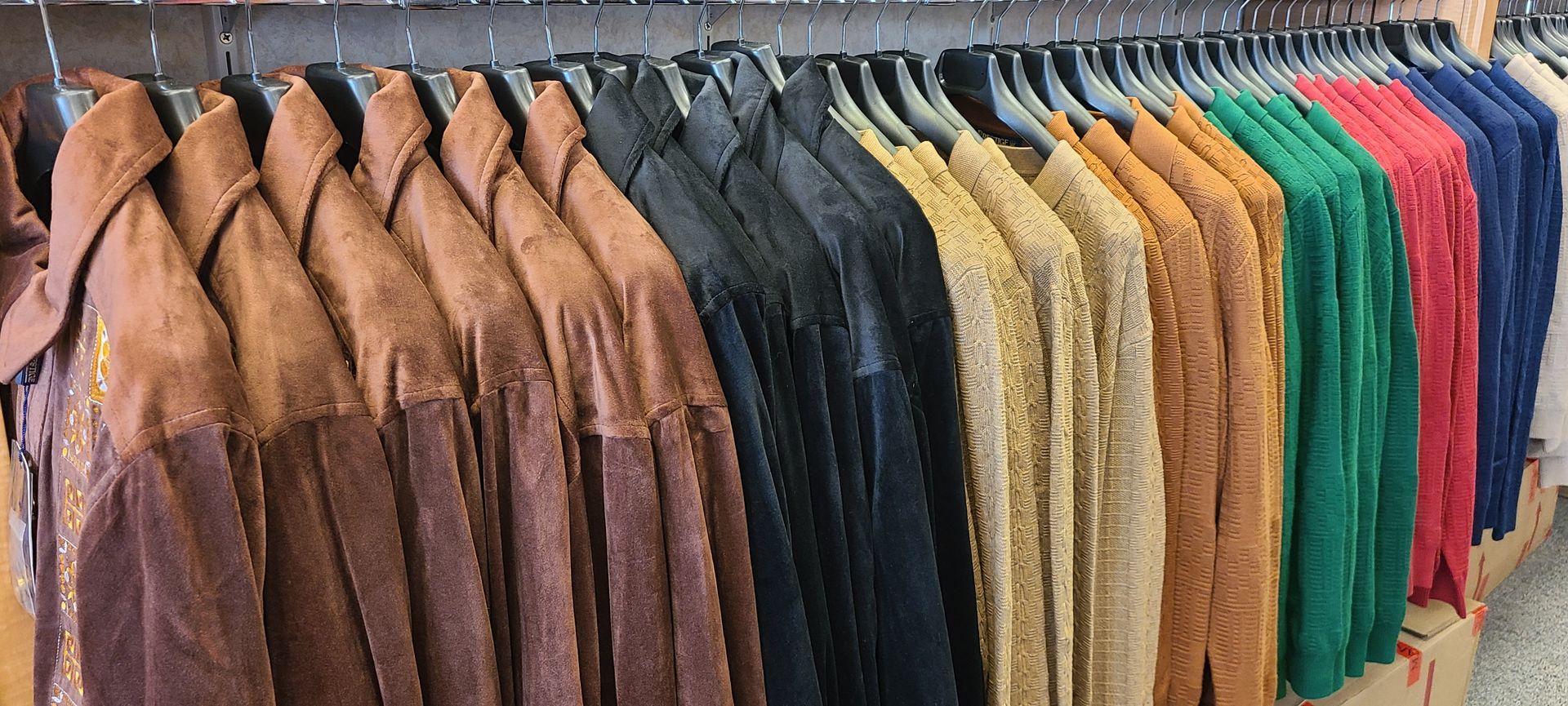 Racks of leather jackets in brown, black, tan, green, red, and blue hanging in a clothing store