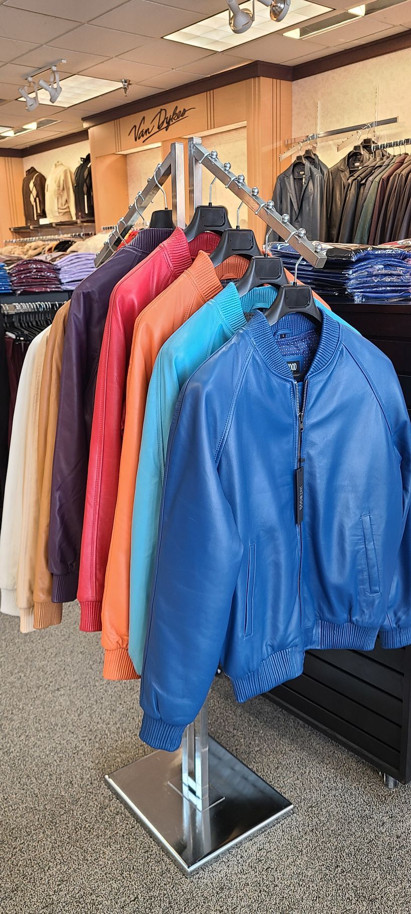 Colorful jackets on a clothing rack in a store, with a bright blue jacket in front