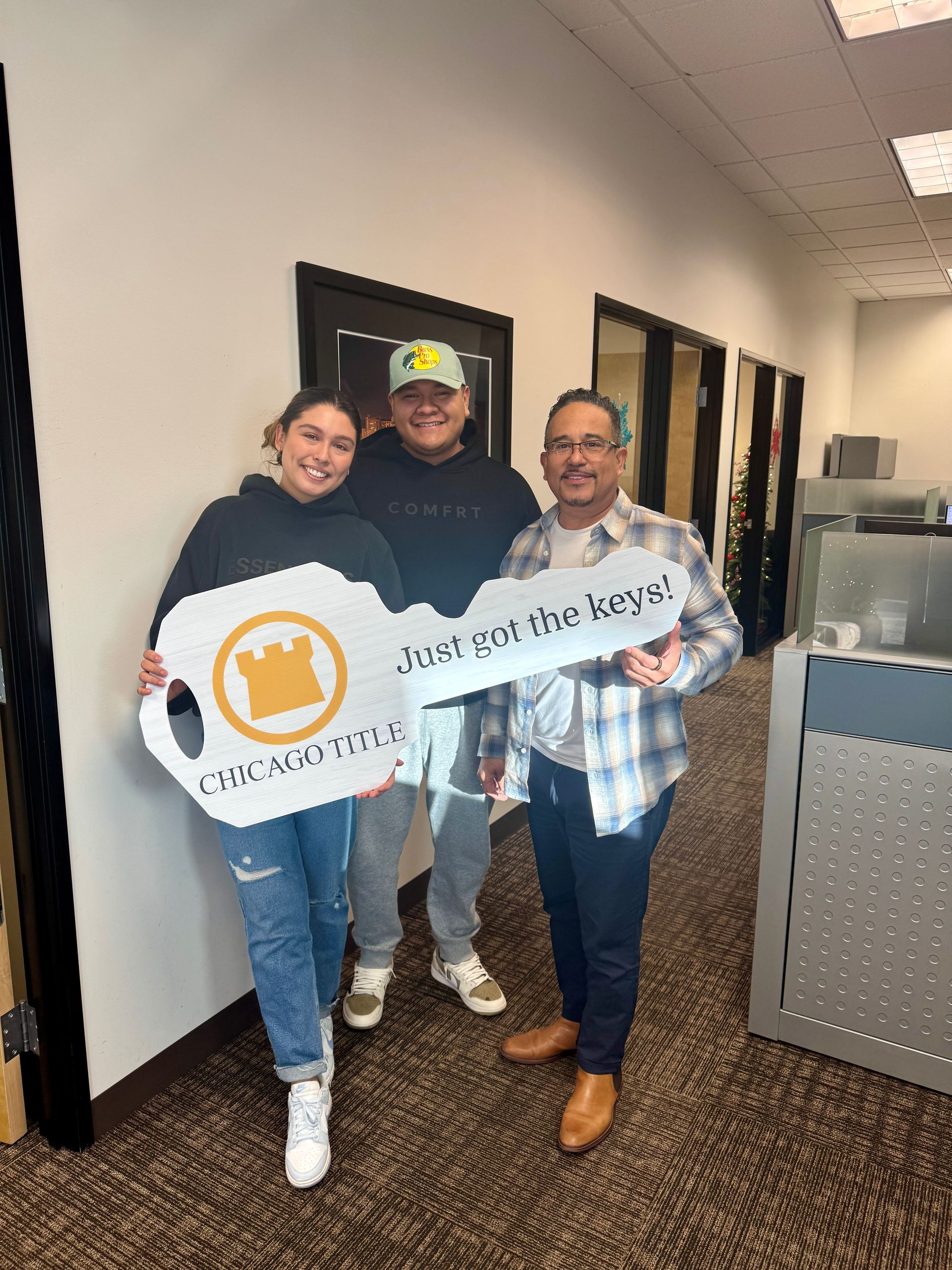 A group of people are standing next to each other in an office holding a key.