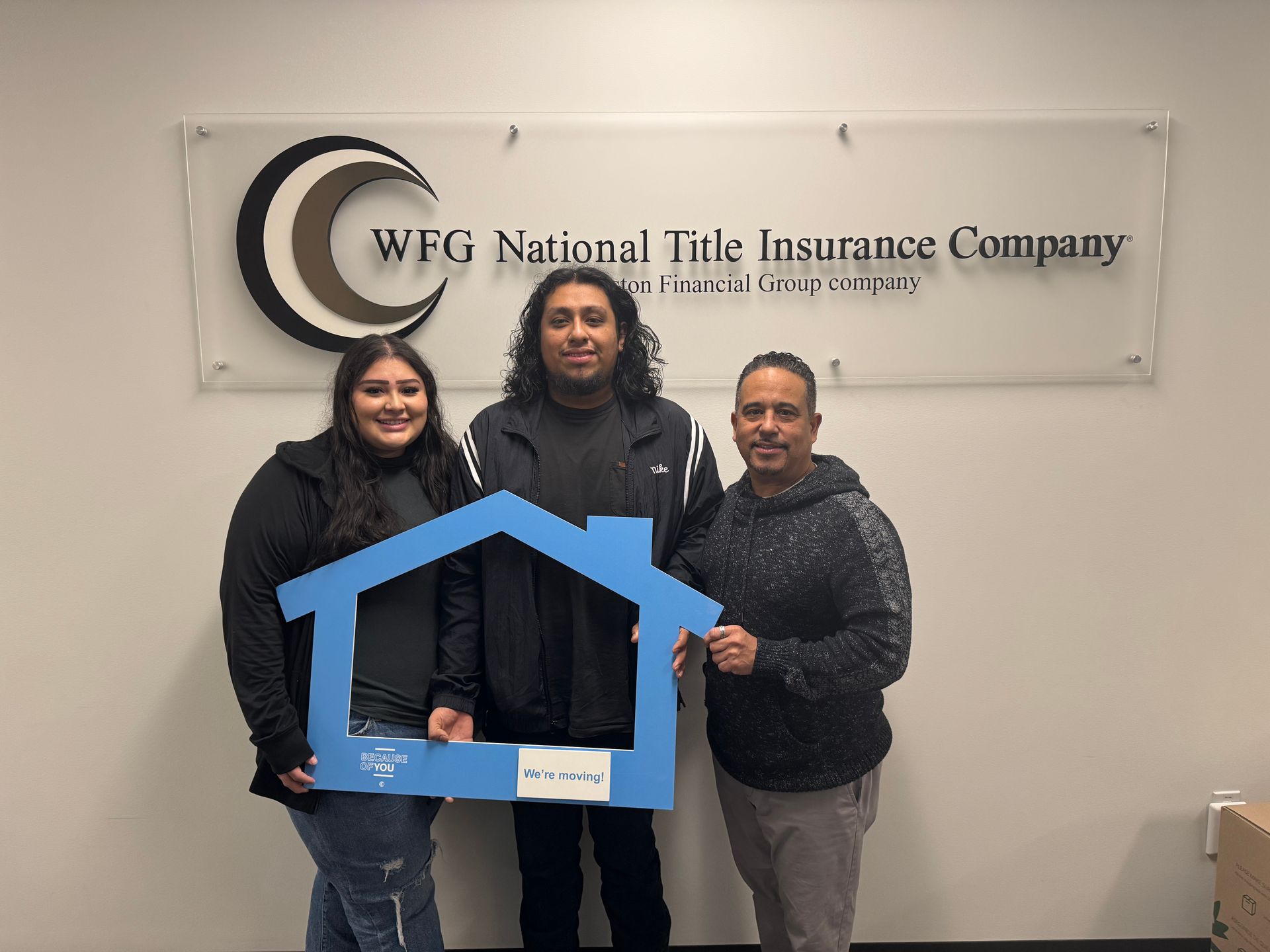 A group of people are standing in front of a sign that says wfg national tile insurance company.