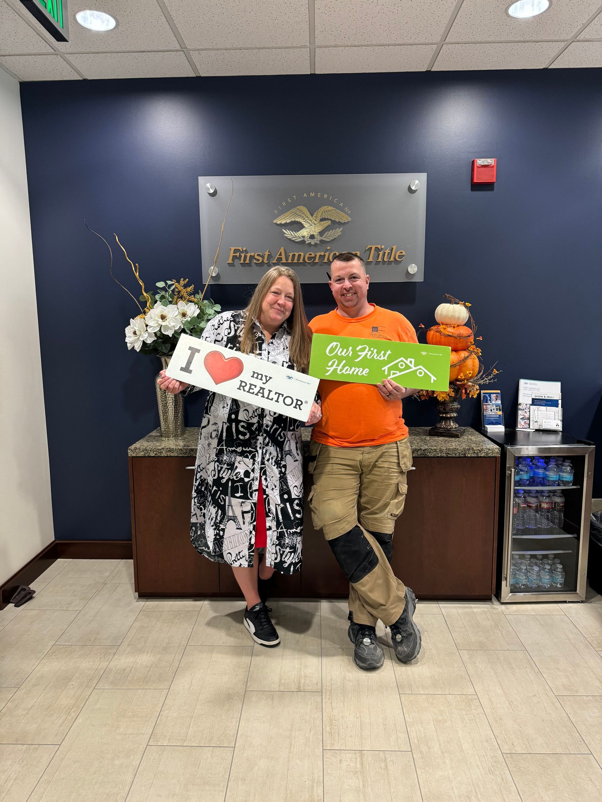 A man and a woman are standing in front of a counter holding signs.