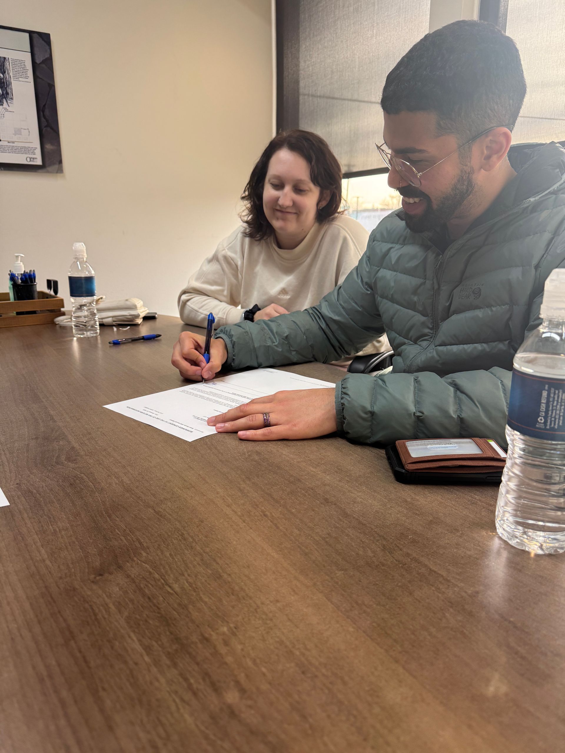 A man and a woman are sitting at a table writing on a piece of paper.