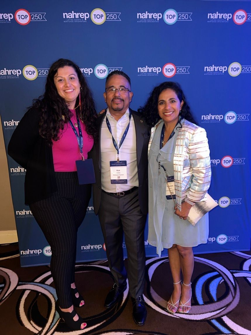 A man and two women are posing for a picture in front of a wall that says nahrop