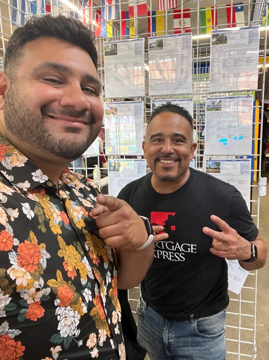 Two men are posing for a picture in front of a display of flags.