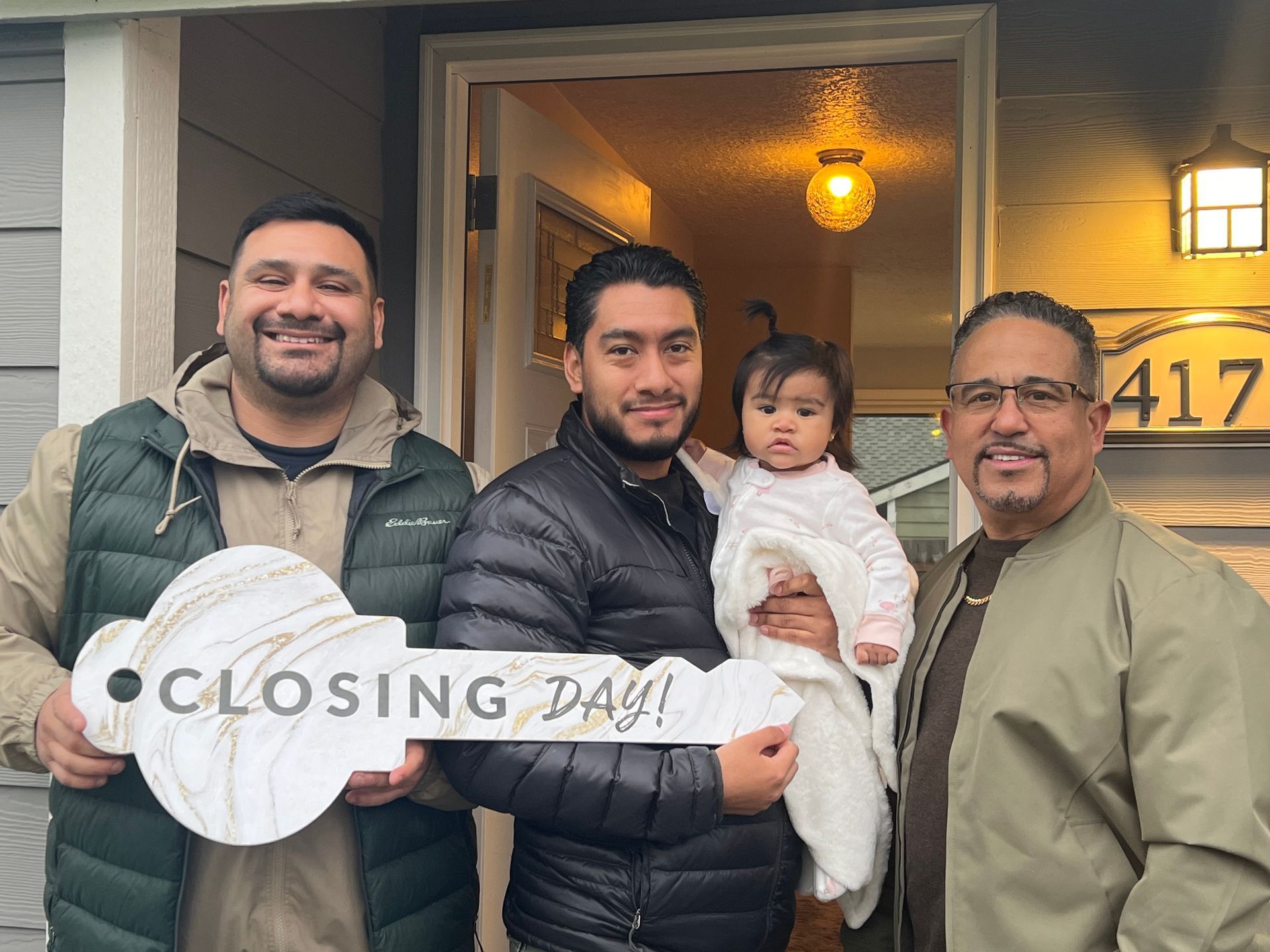 Three men are holding a key in front of a house