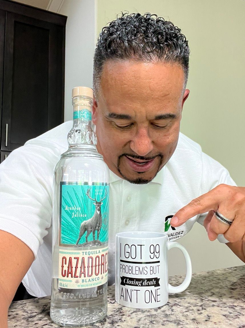 A man is sitting at a counter next to a bottle of tequila and a mug.