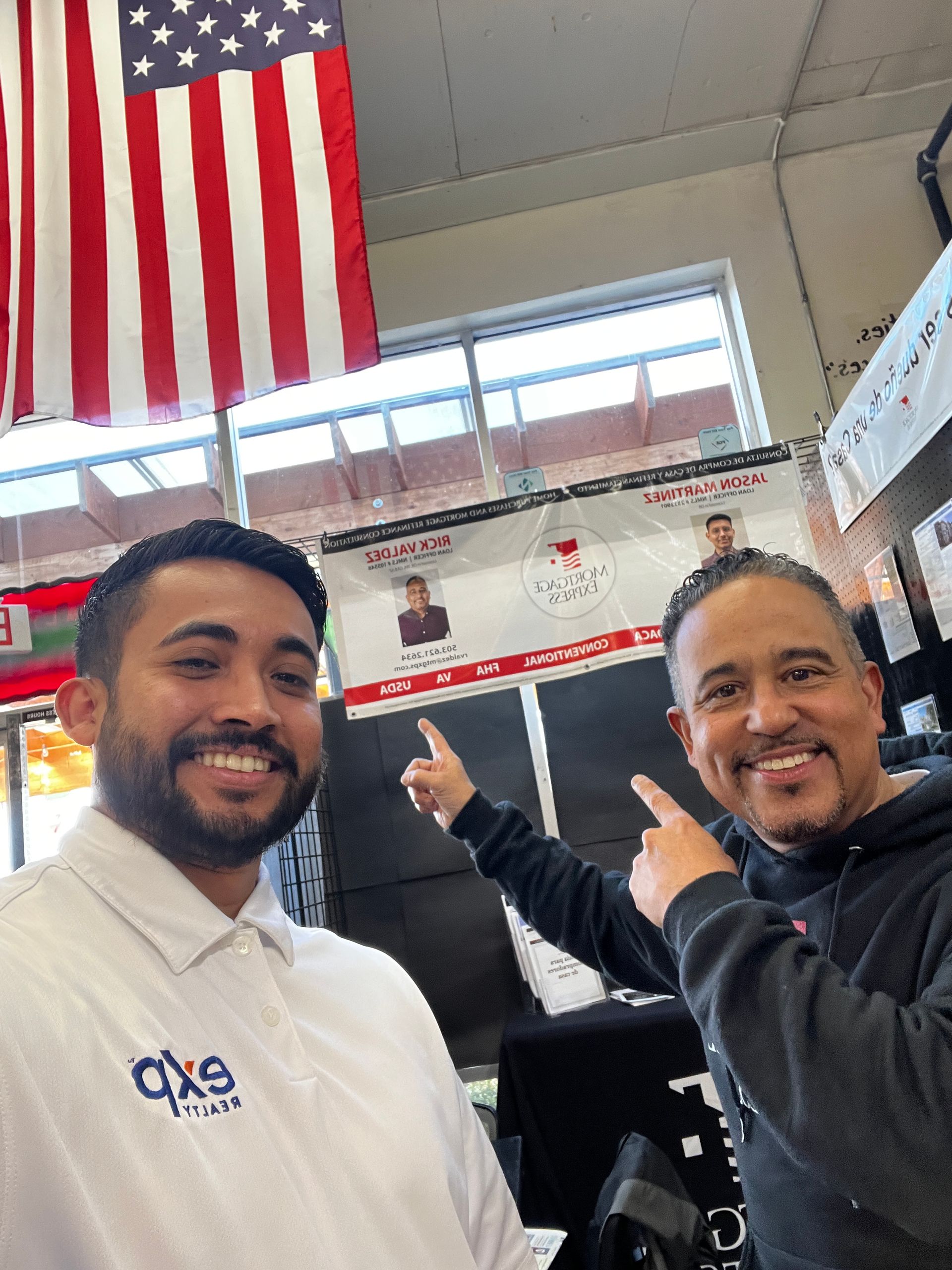 Two men are posing for a picture in front of an american flag.