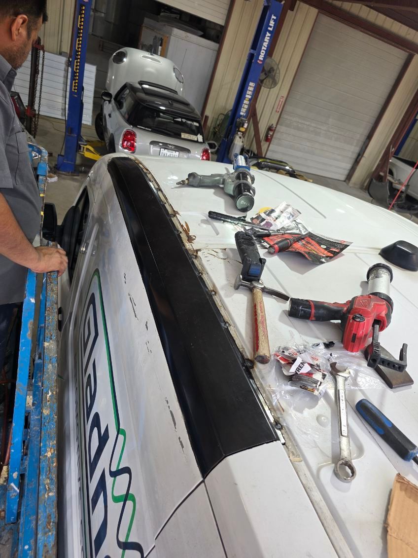 Workshop bench with a large white board, tools, and a person working beside it in a garage.