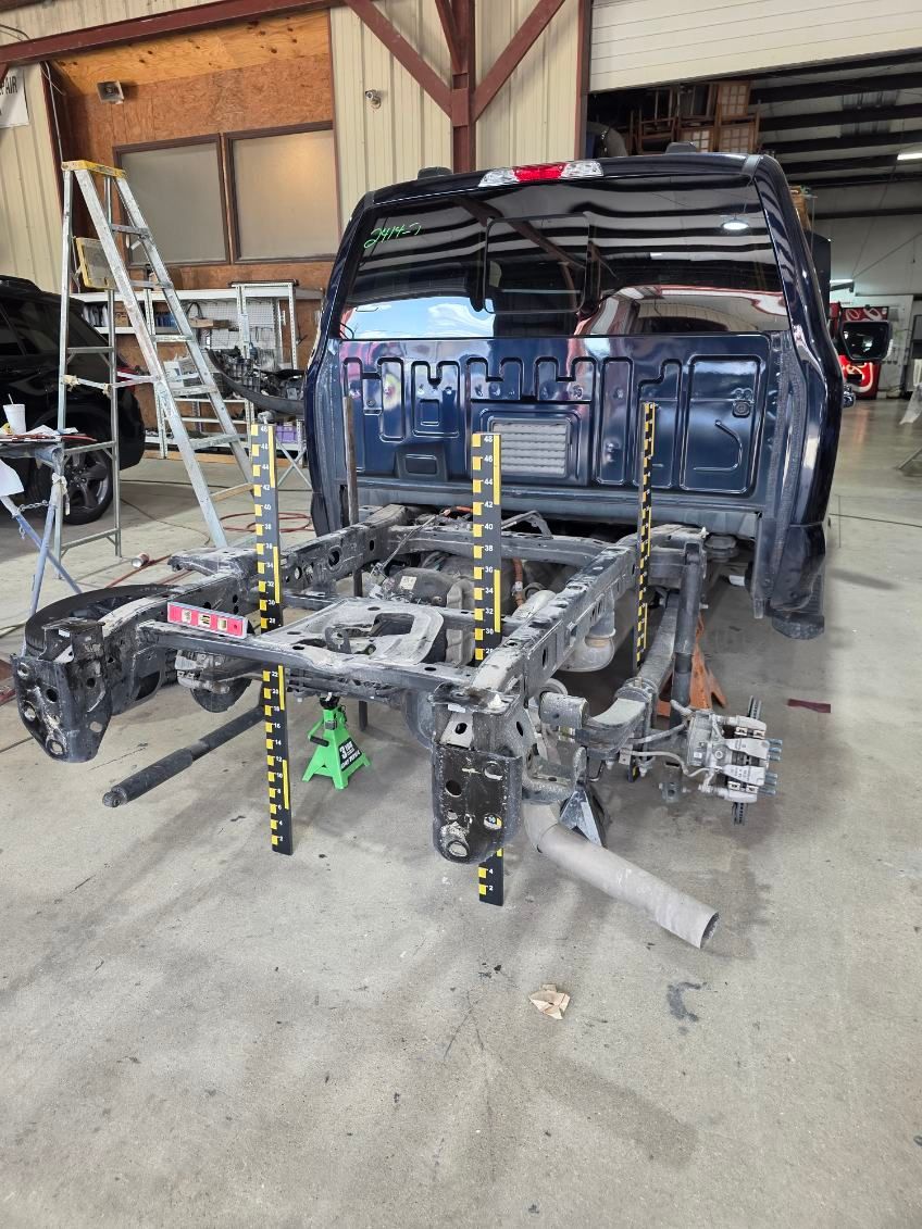 Disassembled dark blue van chassis in a garage workshop with ladders and tools nearby