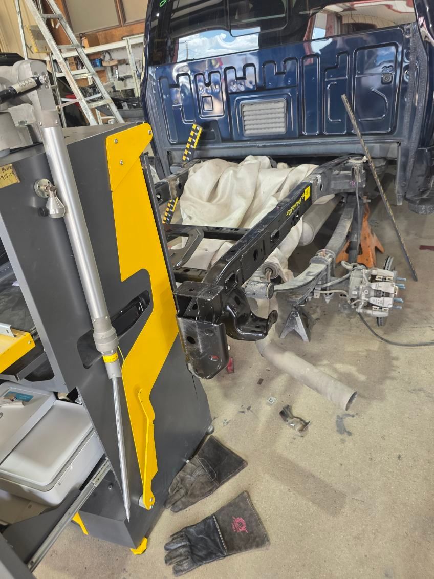 Blue truck cab in a workshop with a hydraulic lift and tools on a concrete floor.