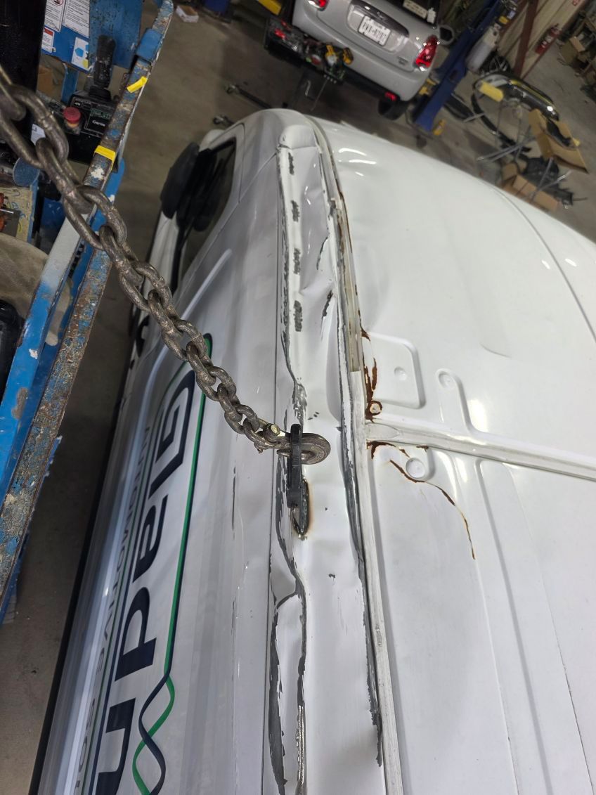 Close-up of a white van with a damaged roof seam in a garage or repair shop